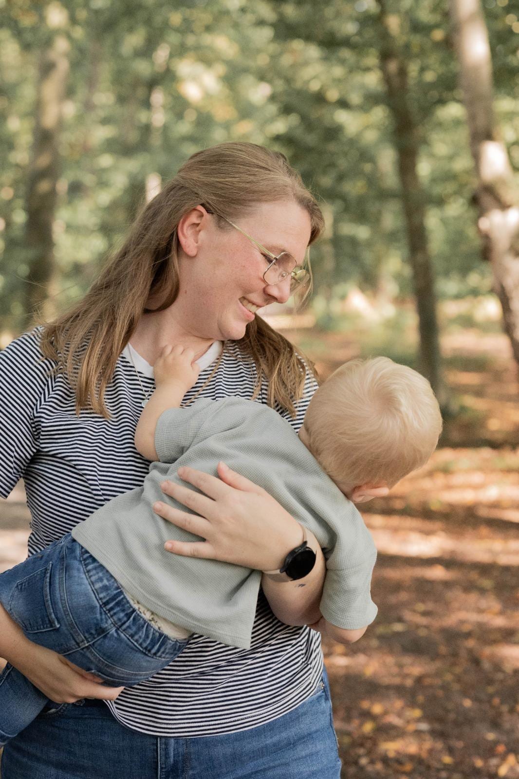 Mama trägt ihren kleinen Sohn im Wald